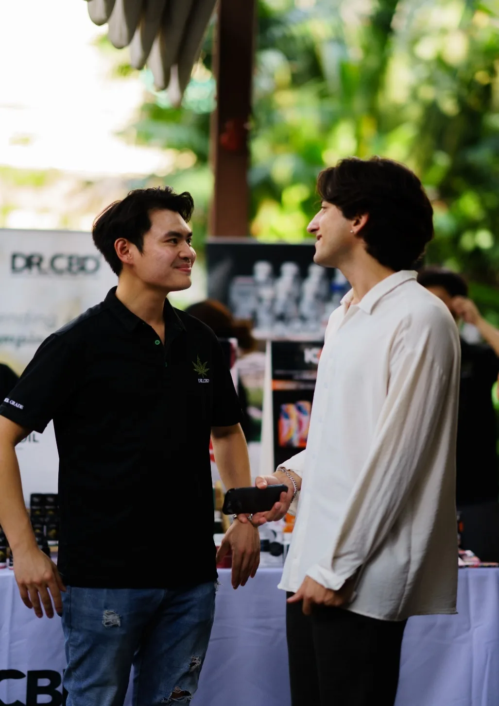Two attendees talk beside the DR CBD booth at MonkeyPod.