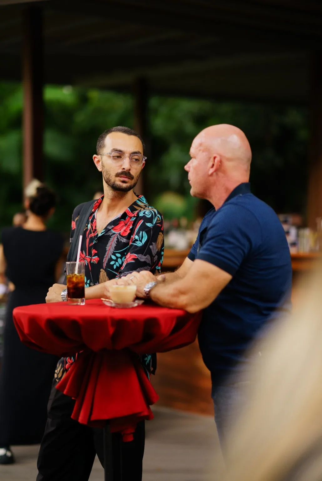 Two attendees converse at a standing table before sunset.