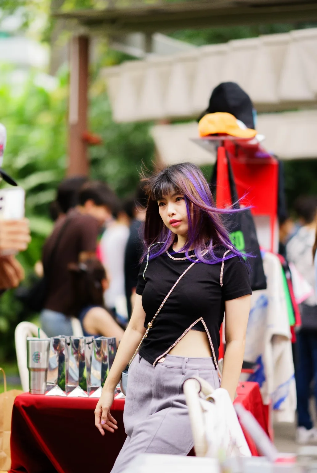 An attendee with purple hair walks past a sponsor booth.