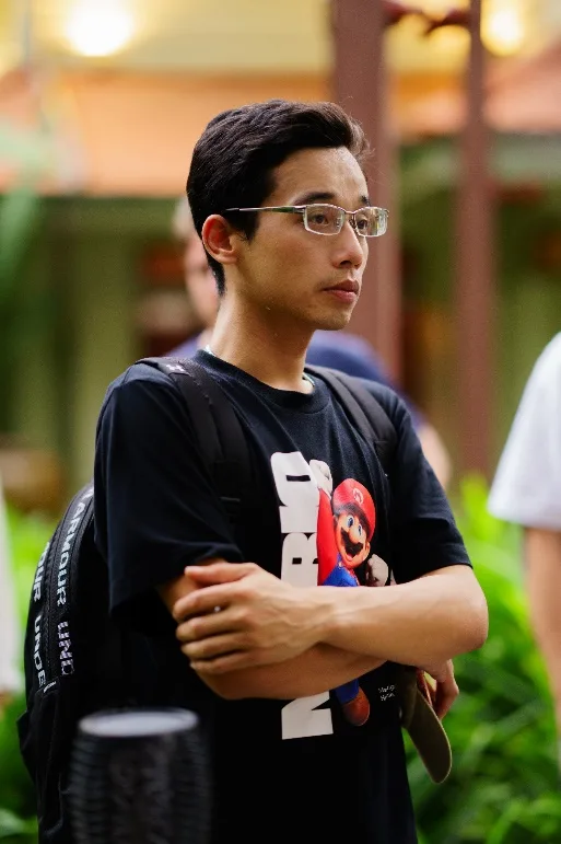 An attendee in glasses listens with his arms folded.