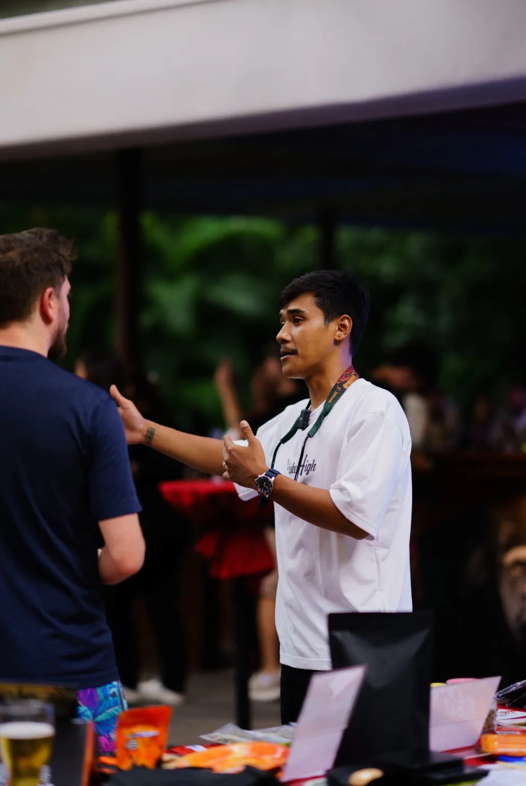 P-Korn from Phuket High speaks with an attendee beside product jars.